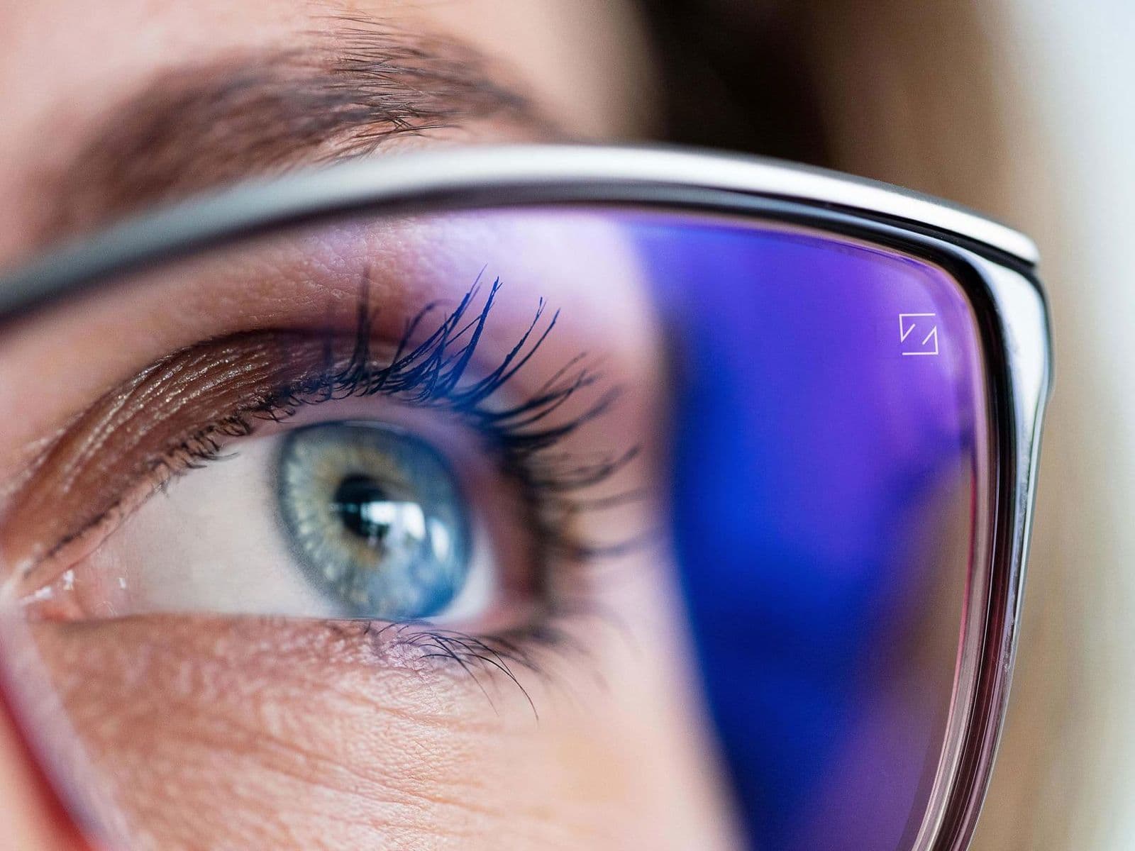 Close-up of a ZEISS lens showing the discreet engraved trademark mark on the blue anti-reflective coating