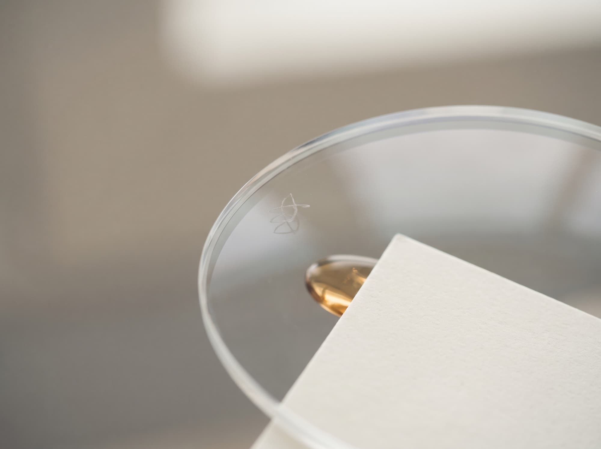 A clear lens held to the light, showing the discreet engraved authenticity marking