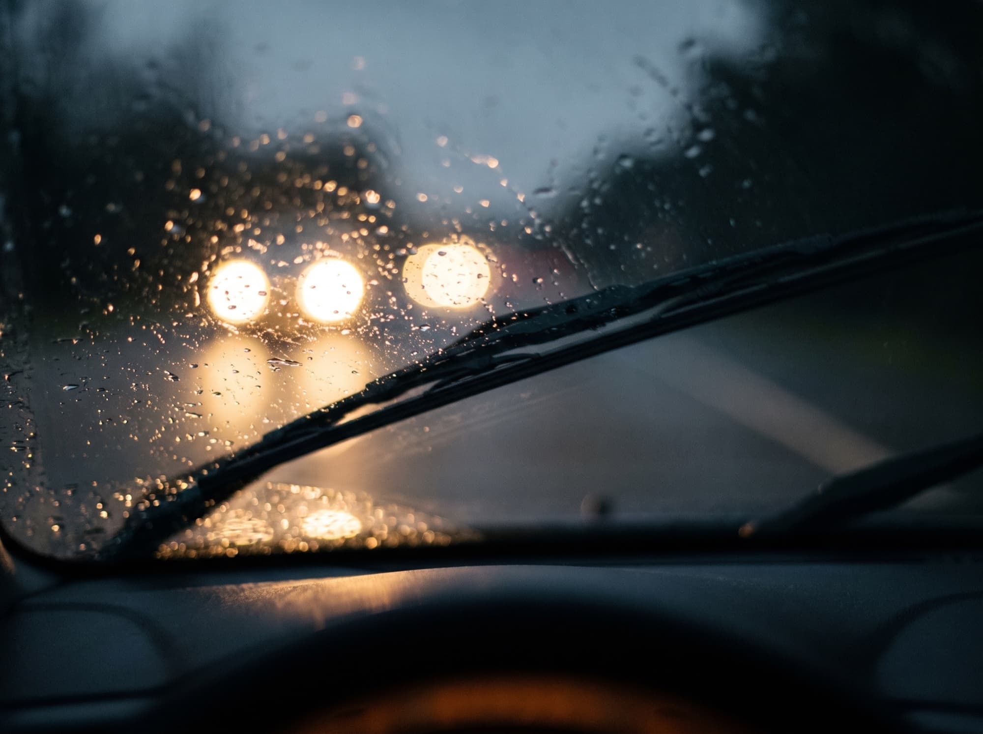 The view through a rainy windscreen at night with softened oncoming lights