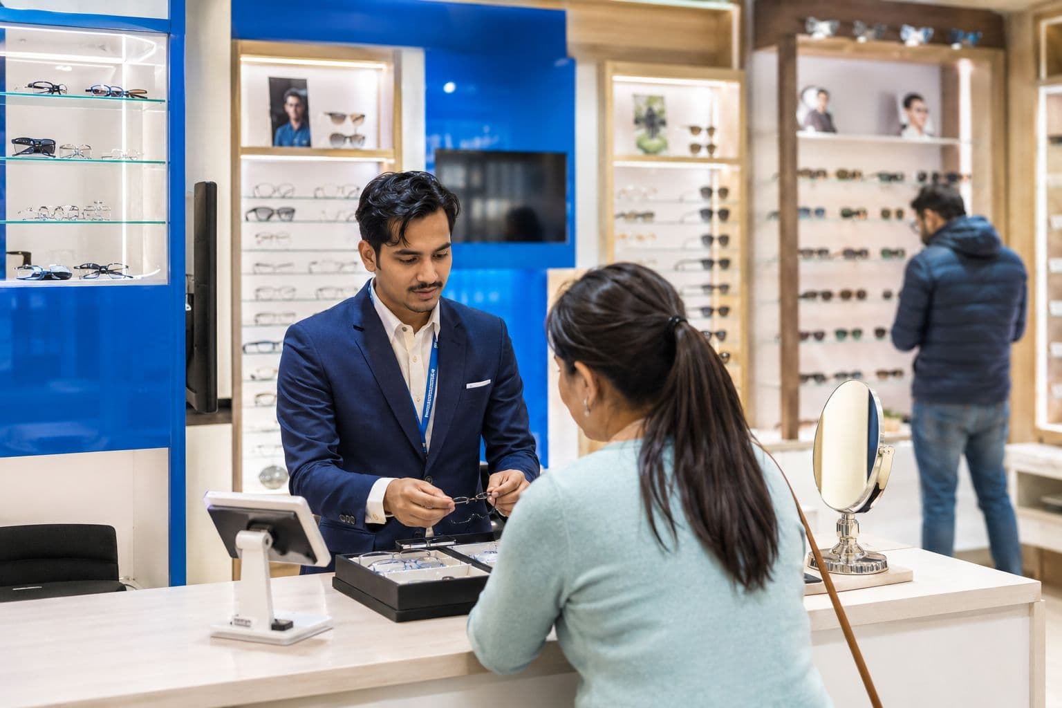 A HighGaze Certified partner store — counter staff helping a customer choose frames beside branded display walls